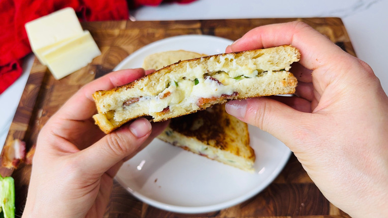 Mains tenant la moitié d'un sandwich au fromage grillé au jalapeño popper
