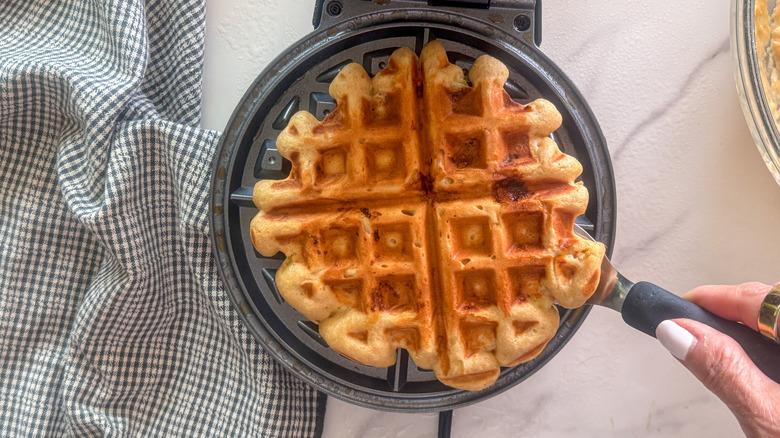 main à l'aide d'une spatule pour retirer la gaufre du gaufrier