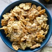 Vue aérienne d'un bol bleu de pâtes soufflées saupoudrées de parmesan et de poivre concassé.