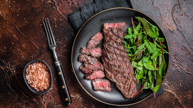 Bavette marinée sur une assiette noire avec salade.
