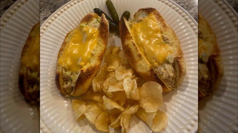 Un sandwich au thon est servi avec des chips et des cornichons