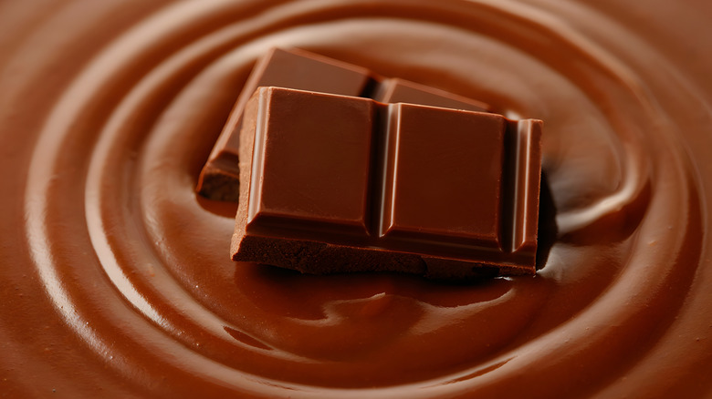Photo en gros plan de carrés de chocolat au-dessus d'une piscine de chocolat fondu ondulé