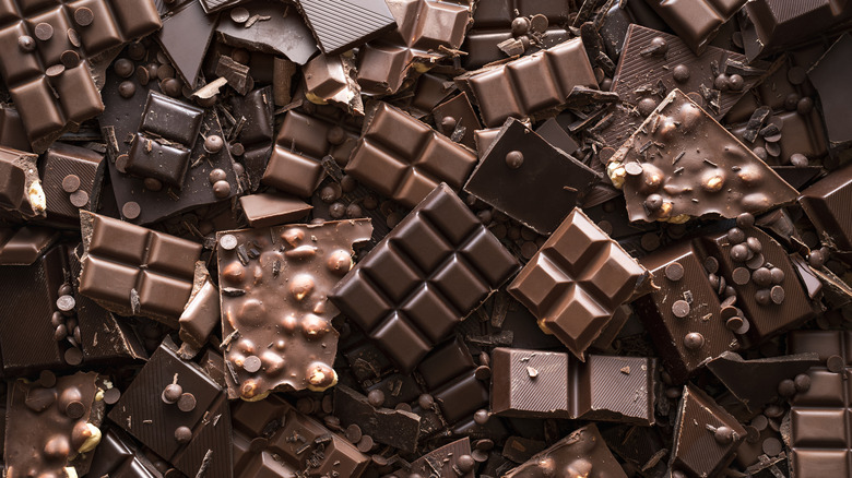 Pile de barres de chocolat cassées, de carrés de chocolat cuits au four et de pépites de chocolat