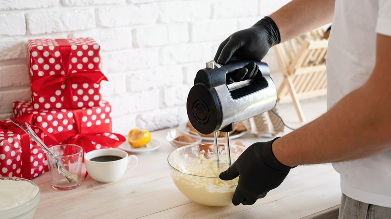 Personne mélangeant Bisquick dans un bol à mélanger en verre avec un batteur électrique portatif