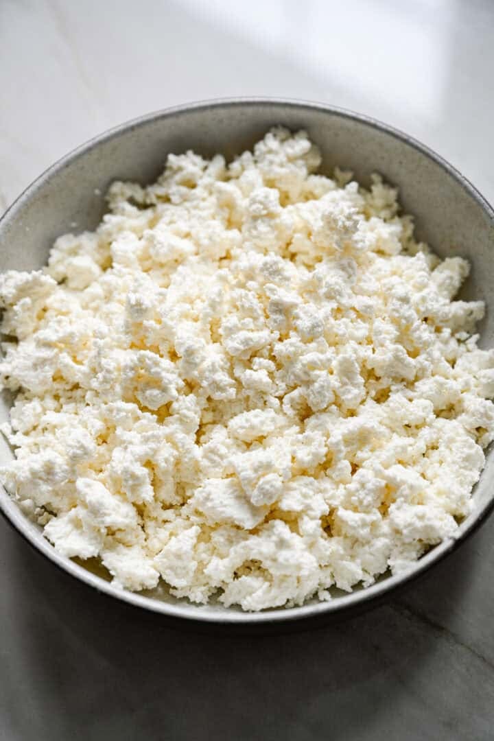 Vue à 45 degrés du fromage cottage fait maison égoutté dans un bol en grès avant d'ajouter de la crème