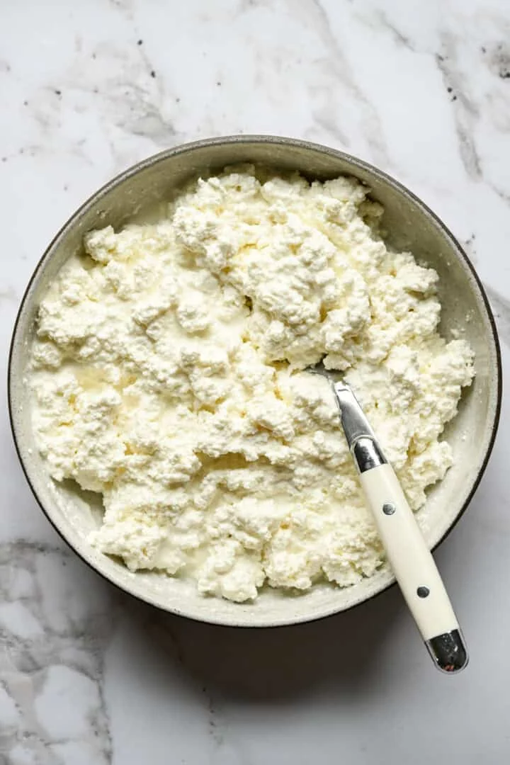 Vue aérienne d'un bol de fromage cottage fait maison avec une cuillère sur un comptoir en marbre