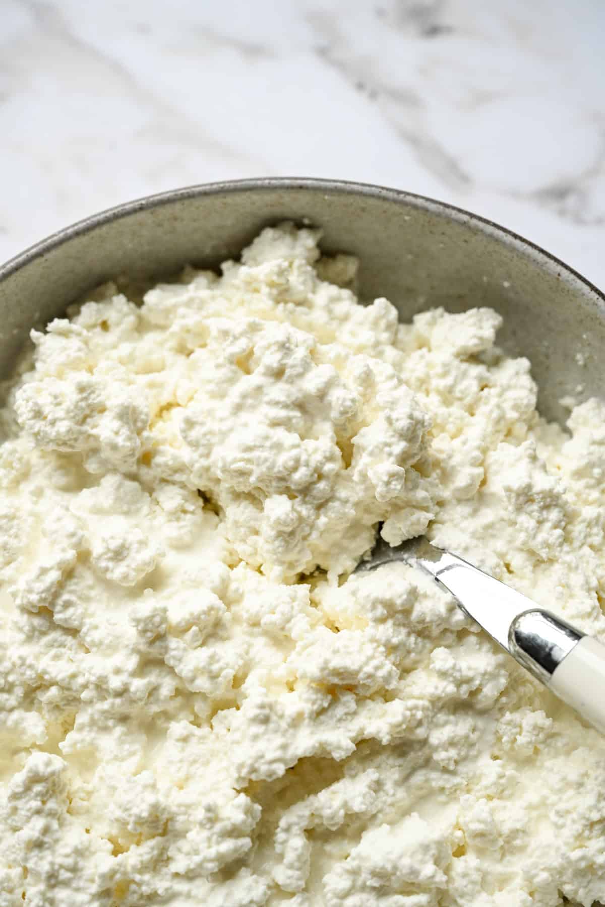Vue rapprochée du fromage cottage crémeux fait maison dans un bol avec une cuillère