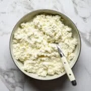 Vue aérienne du fromage cottage crémeux fait maison dans un bol avec une cuillère en remuant la crème épaisse