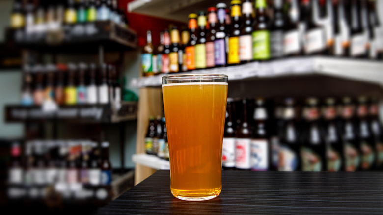 Une pinte de bière entourée de bouteilles de bière
