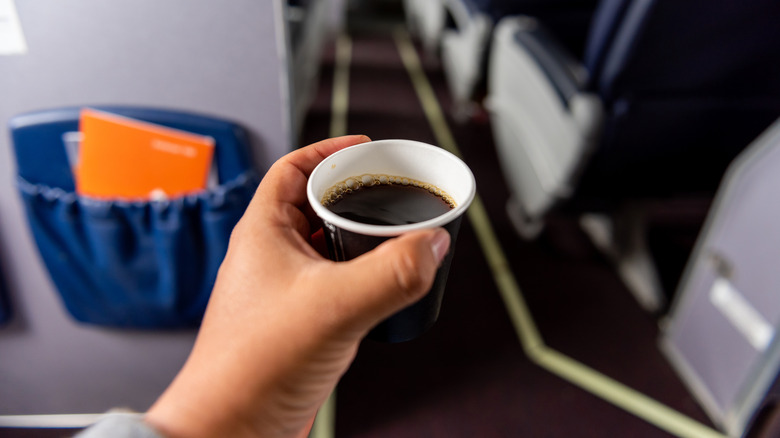 Tasse de café dans un avion tendue au milieu de l'allée.