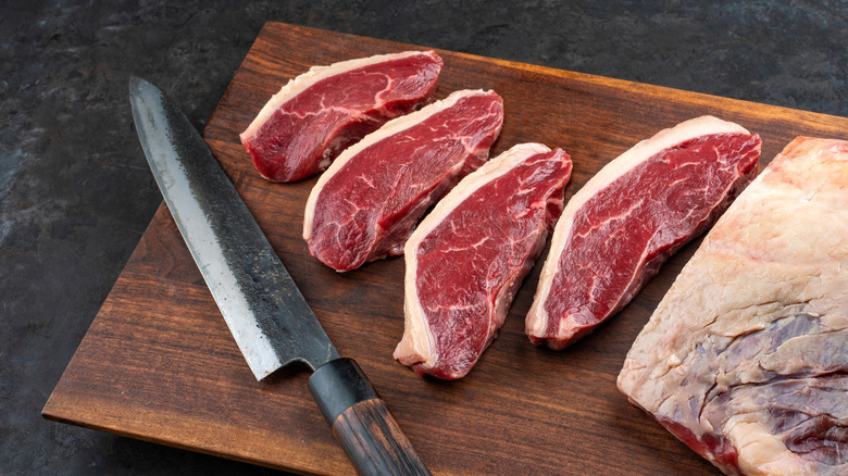Steaks de picanha tranchés sur une planche à découper.