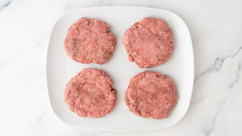 Une assiette blanche garnie de quatre galettes de burger