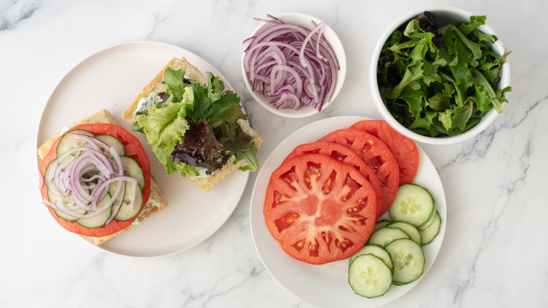 Un burger garni de tomates, concombres, oignons et légumes-feuilles