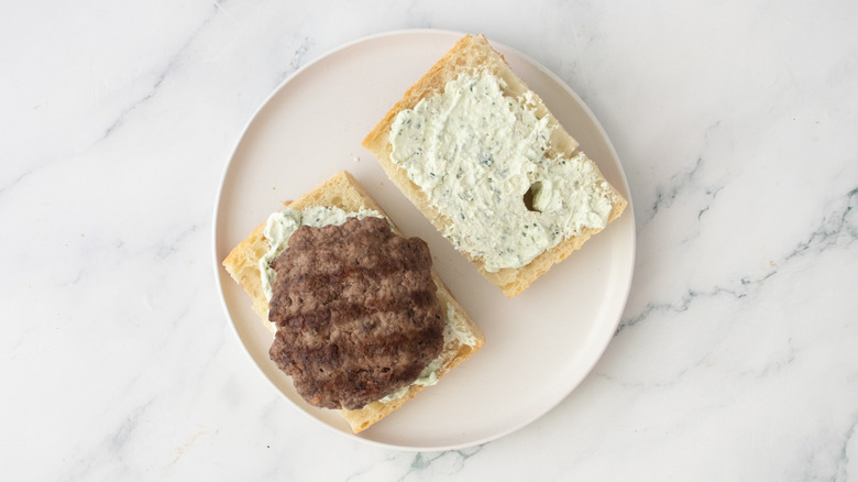 Une galette de burger grillée posée sur une portion de pain façon miche
