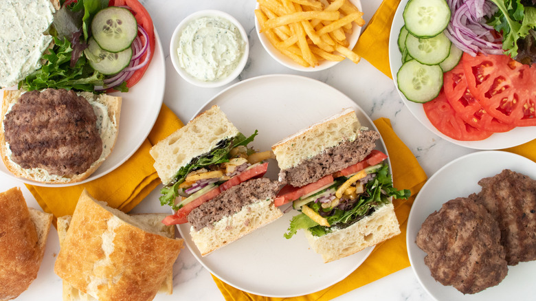Plan aérien d'un hamburger gyroscopique coupé en deux et bien empilé avec des garnitures et des condiments sur le côté.