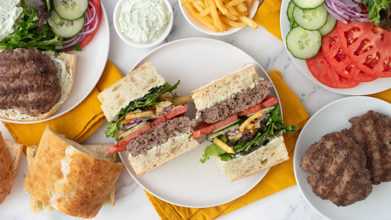 Photo aérienne d'un hamburger gyroscopique coupé en deux et bien empilé avec des garnitures et des condiments sur le côté