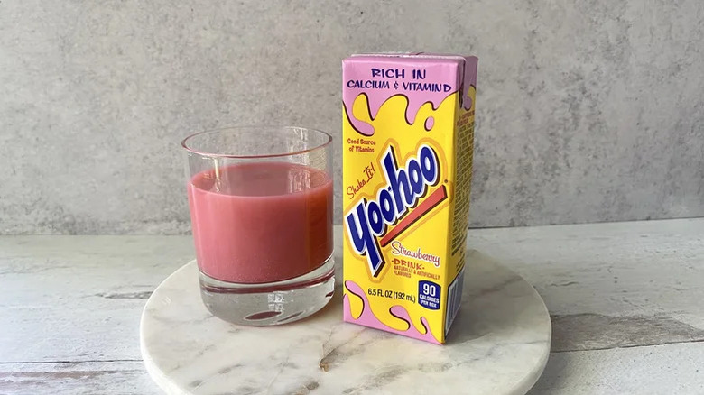 Un récipient de boisson aux fraises Yoo-Hoo se trouve à côté d'un verre rempli de boisson Yoo-Hoo