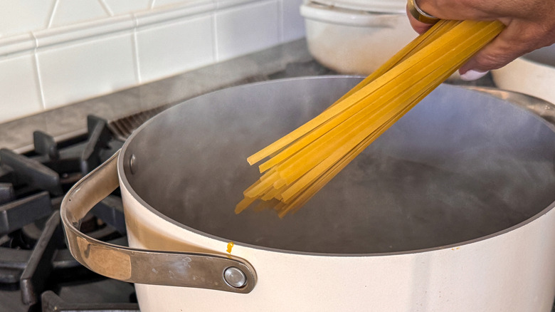 main ajoutant des fettuccine au pot