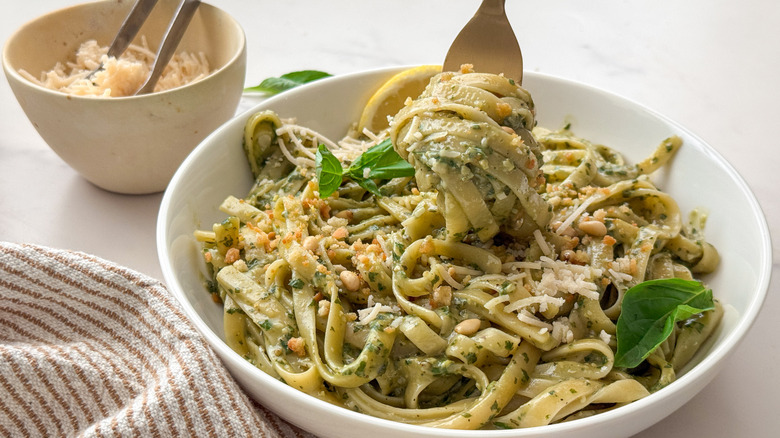 Fettuccine au pesto tourbillonnée sur une fourchette sur un grand bol de pâtes