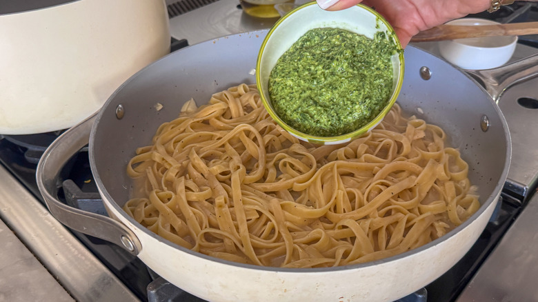 Bol de pesto entrant dans les pâtes fettuccine dans la poêle