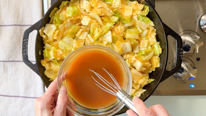 Fouetter la sauce pour le chou cowboy dans un petit bol en verre sur une poêle sur la cuisinière