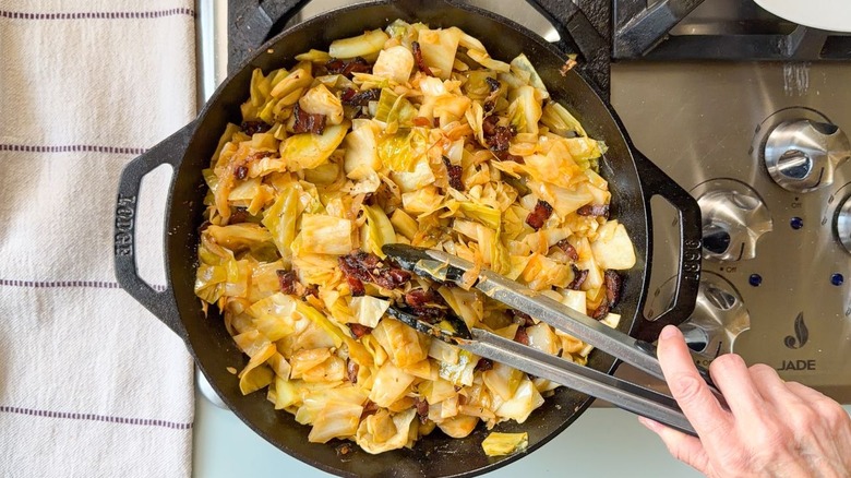 Ajouter des morceaux de bacon croustillants au chou cowboy dans une poêle avec des pinces
