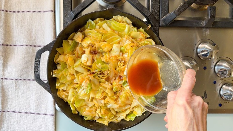 Verser la sauce dans la poêle du chou cowboy sur la cuisinière