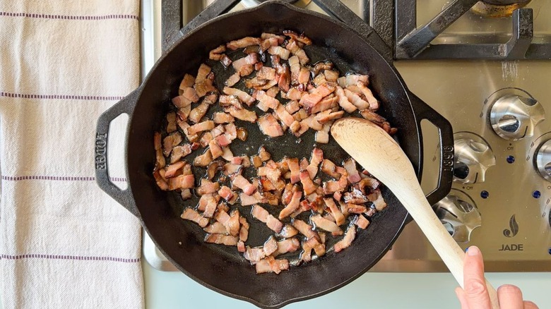 Lardons de bacon cuisant dans une poêle en fonte sur la cuisinière