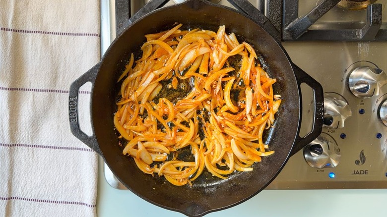 Oignons sautés et épices dans une poêle en fonte sur la cuisinière