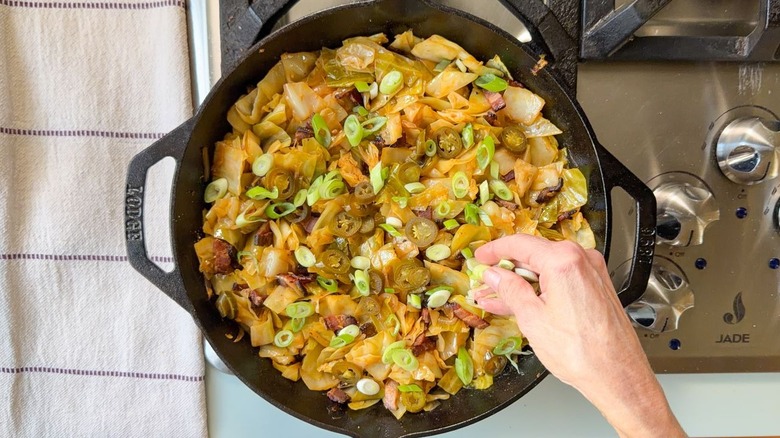 Ajouter des jalapeños marinés et des oignons verts tranchés au chou cowboy dans la poêle