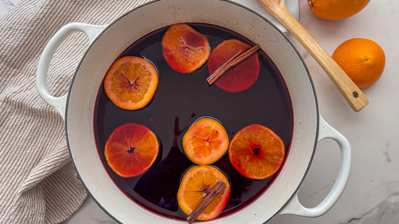pot de vin chaud avec des tranches d'orange et des bâtons de cannelle