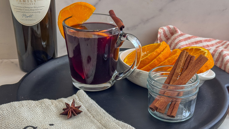 tasse de vin chaud sur plateau avec des tranches d'orange et des bâtons de cannelle