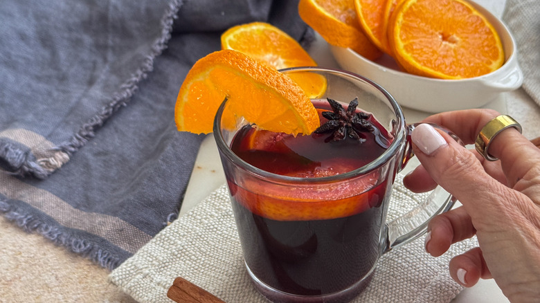 main tenant une tasse de vin chaud avec des garnitures