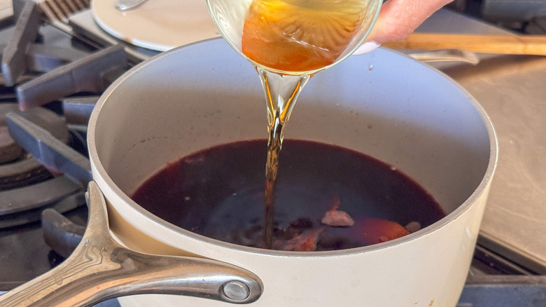 verser du cognac dans une casserole avec du vin chaud