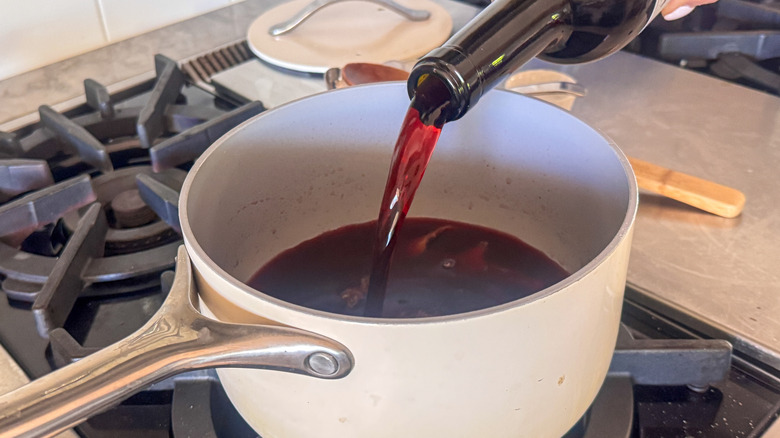 Vin rouge versant de la bouteille dans la casserole
