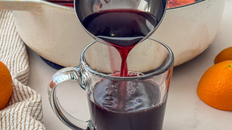 Louche versant du vin chaud rouge dans une tasse transparente