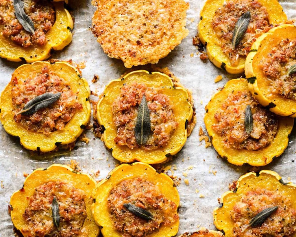 Vue rapprochée des rondelles de courge Delicata farcies et d'un croustillant de parmesan sur parchemin.