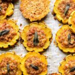 Vue rapprochée des rondelles de courge Delicata farcies et d'un croustillant de parmesan sur parchemin.