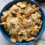 Vue aérienne de pâtes soufflées dans un bol bleu à côté d'un morceau de parmesan et d'un plat de poivre.