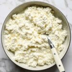 Vue aérienne d'un bol de fromage cottage fait maison avec une cuillère sur un comptoir en marbre