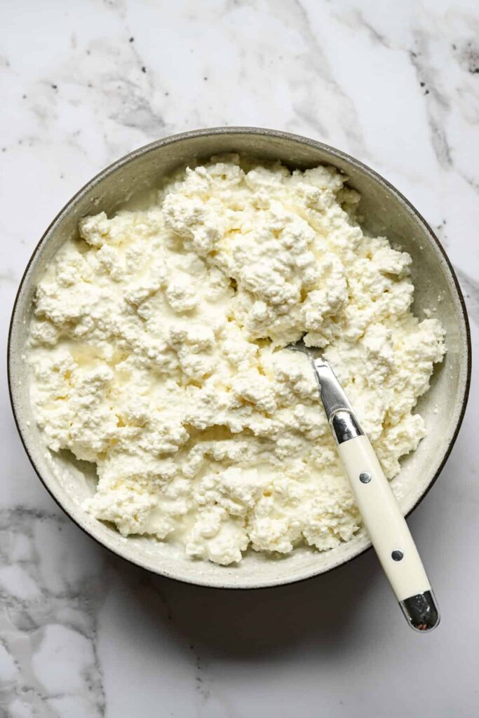 Vue aérienne d'un bol de fromage cottage fait maison avec une cuillère sur un comptoir en marbre